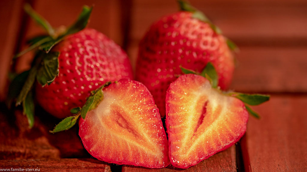 aufgeschnittene Erdbeere vor zwei ganzen Erdbeeren