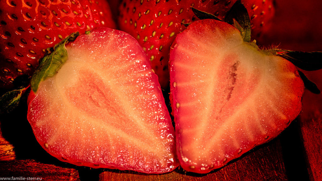 aufgeschnittene Erdbeere vor zwei ganzen Erdbeeren