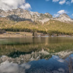 die Berge und der weißblaue Himmel spiegeln sich dem ruhigen Wasser des Hintersees bei Ramsau im Berchtesgadener Land