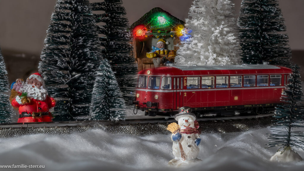 einen Schienenbus fährt durch das winterliche Weihnachtsdorf