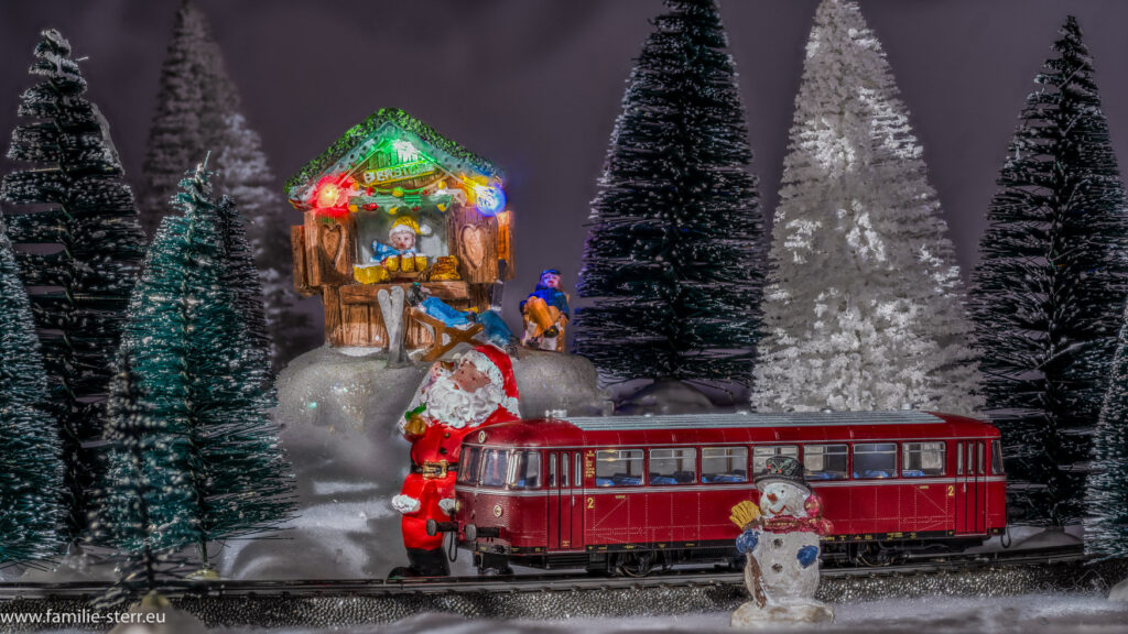 einen Schienenbus fährt durch das winterliche Weihnachtsdorf