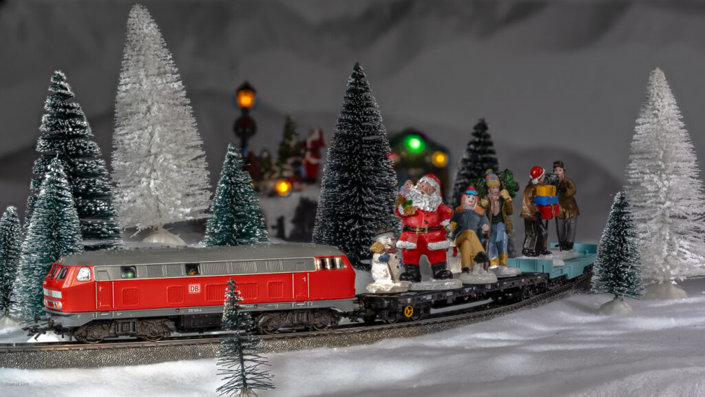 Figuren aus dem Weihnachtsdorf fahren auf dem Zug der Modelleisenbahn am Ende der Weihnachtszeit ins Sommerlager