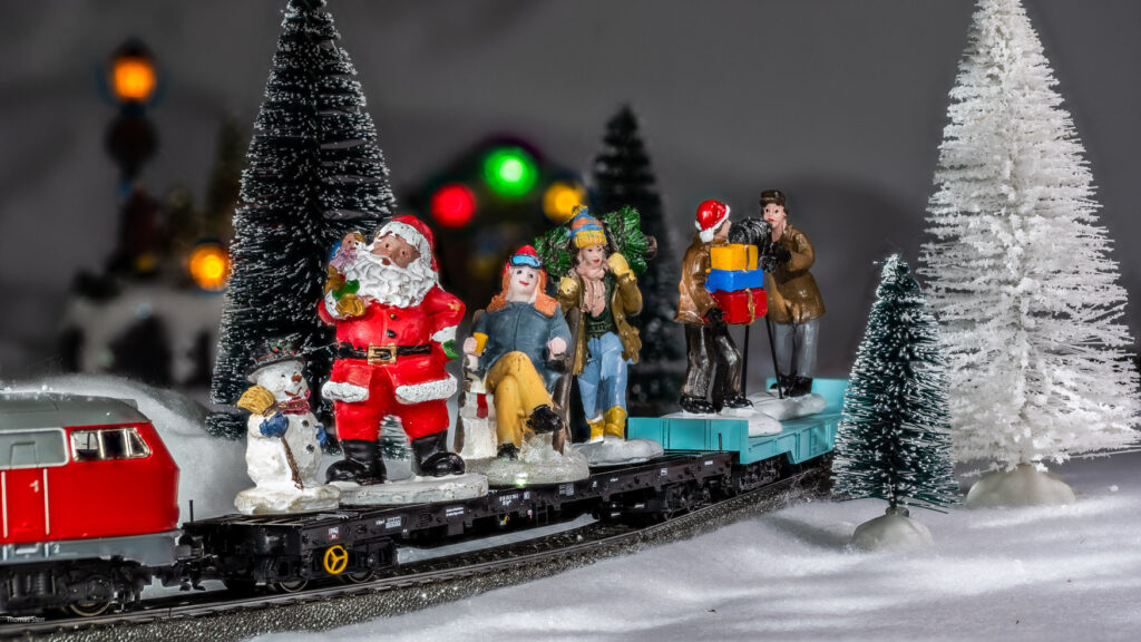 Figuren aus dem Weihnachtsdorf fahren auf dem Zug der Modelleisenbahn am Ende der Weihnachtszeit ins Sommerlager