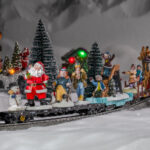 Figuren aus dem Weihnachtsdorf fahren auf dem Zug der Modelleisenbahn am Ende der Weihnachtszeit ins Sommerlager