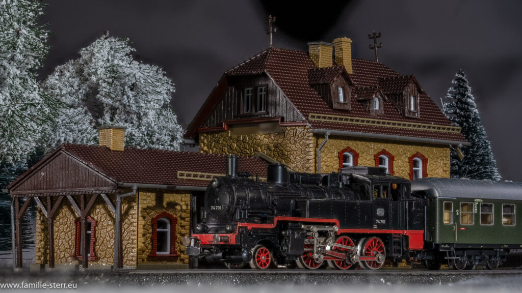 eine kleine Dampflok mit einem historischen Personenwagen steht im winterlichen Bahnhof - Märklin H0