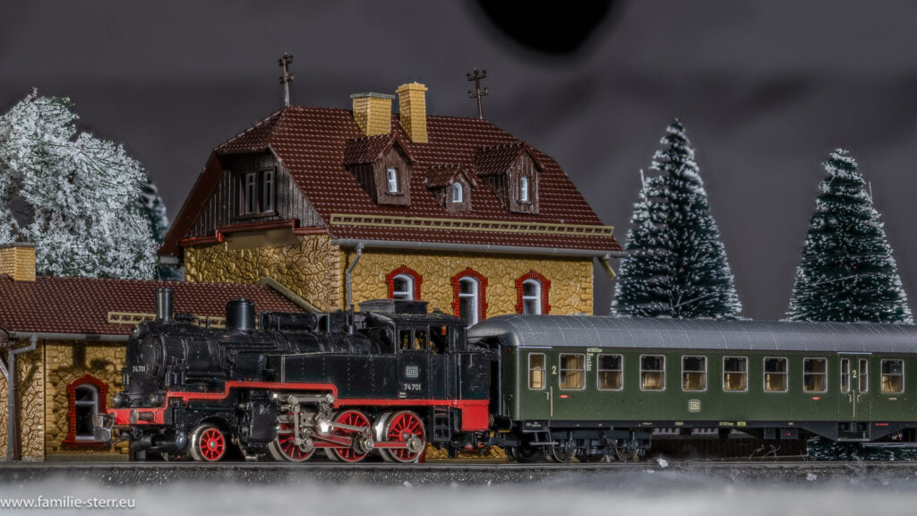 eine kleine Dampflok mit einem historischen Personenwagen steht im winterlichen Bahnhof - Märklin H0